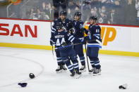 Winnipeg Jets' Josh Morrissey (44), Blake Wheeler (26), Mark Scheifele (55) and Nate Schmidt (88) celebrate Scheifele's hat-trick goal against the New Jersey Devils, during the third period of an NHL hockey game Friday, Dec. 3, 2021, in Winnipeg, Manitoba. (John Woods/The Canadian Press via AP)