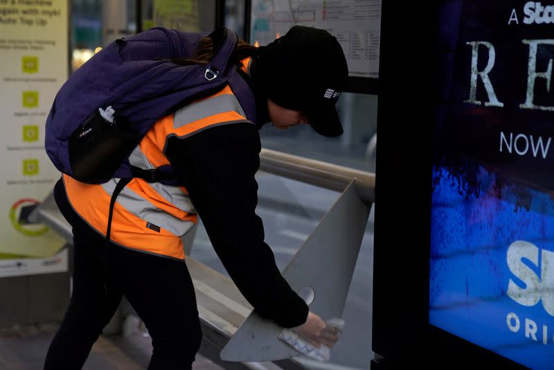 An essential worker sanitises a tram stop under COVID-19 lockdown restrictions in Melbourne