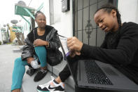 Miesha Clarke sits with her 10-year-old son, Ezekiel West, as he opens his new K12/Stride school loaner laptop computer outside his home in Los Angeles on Sunday, Jan. 15, 2023. Before the pandemic shutdowns, he was shuffled from school to school when educators couldn’t address his impulsive behavior. (AP Photo/Damian Dovarganes)