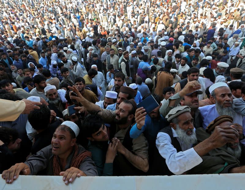 Afghan men wait to collect tokens needed to apply for the Pakistan visa, in Jalalabad, Afghanistan