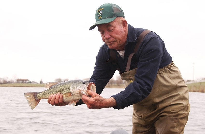 Ken Russell, District 4 fisheries manager for the Illinois Department of Natural Resources, holds a largemouth bass before tossing it into Citizens Lake in Monmouth.