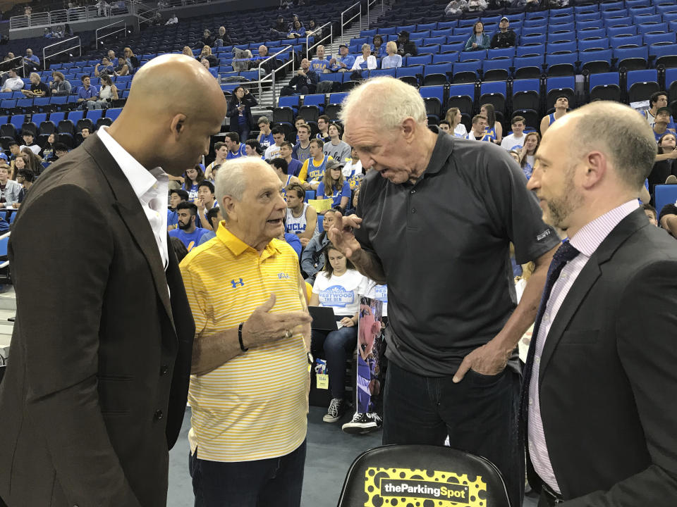 In this Feb. 29, 2020, photo provided by UCLA Athletics, Hep Cronin, second from left, talks with Richard Jefferson, left, and Bill Walton second from right, and Dave Pasch courtside at Pauley Pavilion in Los Angeles. Jefferson, Pasch and Walton were the ESPN crew for UCLA's game against Arizona. Hep had not seen his son, UCLA coach Mick Cronin, for over a year until the Bruins defeated Michigan State in the First Four. Hep has become an unlikely celebrity during the Bruins' run to the Final Four in his son's second season in Westwood. (UCLA Athletics via AP)