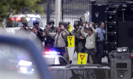 Evacuees raise their hands as they are escorted from the scene of a shooting at the Washington Navy Yard in Washington, September 16, 2013. REUTERS/Jason Reed