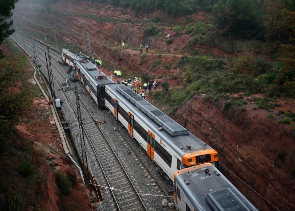 Rescue workers survey the scene after the train derailed (Albert Gea/Reuters)