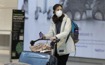 A woman wears a mask as she walks at Heathrow Airport Terminal 5, in London, Tuesday, March 24, 2020. Britain's Prime Minister Boris Johnson on Monday imposed its most draconian peacetime restrictions due to the spread of the coronavirus on businesses and social gatherings. For most people, the new coronavirus causes only mild or moderate symptoms. For some it can cause more severe illness.(AP Photo/Kirsty Wigglesworth)