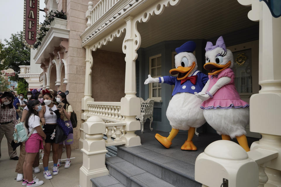 Visitors wearing face masks line up to take selfie with the iconic cartoon characters Donald Duck and Daisy Duck at the Hong Kong Disneyland, Friday, Sept. 25, 2020. Hong Kong Disneyland reopened its doors to visitors after closed temporarily due to the coronavirus outbreak. (AP Photo/Kin Cheung)