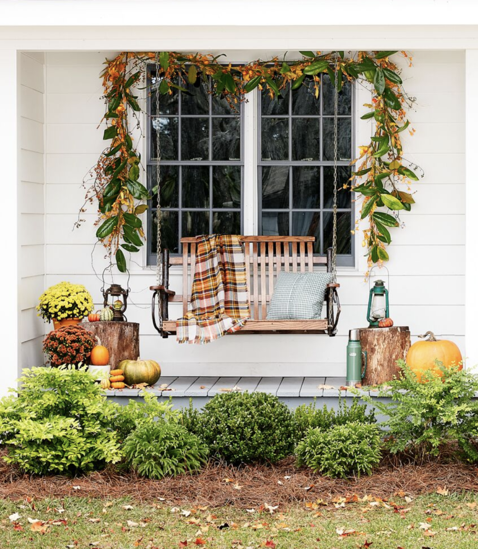 fall porch with a rustic swing and plaid blanket