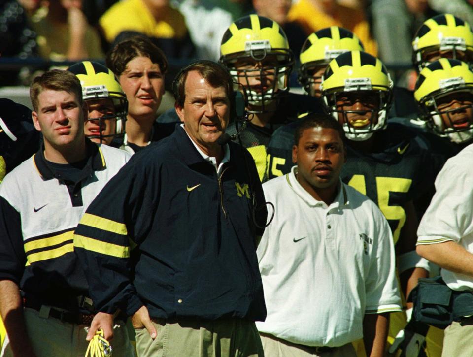 Michigan football coach Lloyd Carr, center, and team watch from the action from the sidelines in this Oct. 11, 1997 file photo. Carr takes his No. 5 ranked Wolverines to East Lansing for a showdown with rival Michigan State, Saturday, Oct. 25, 1997. (AP Photo/Duane Burleson)