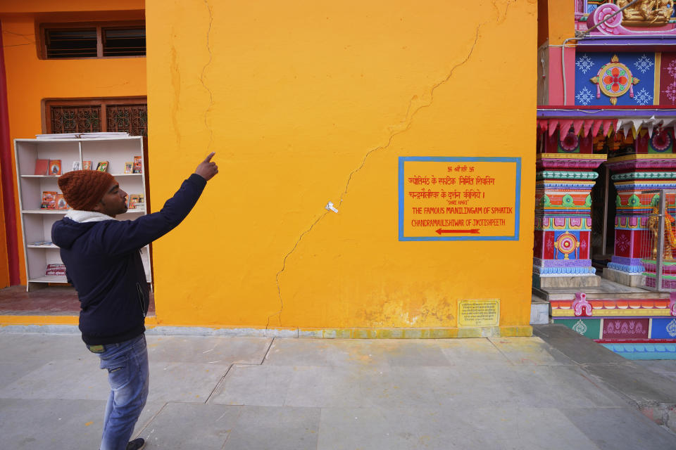 A person shows a long, jagged crack running across one of the front walls in the famed Adi Shankaracharya monastery, in Joshimath, in India's Himalayan mountain state of Uttarakhand, Jan.19, 2023. For decades, scientists have warned that the holy town, built on piles of debris left behind from years of landslides and earthquakes, could not withstand heavy construction. A report from 1976 said that Joshimath's location along a slope and over a geological fault line made it inherently unstable. Its foundation of loose top soil and soft rocks had a carrying limit. (AP Photo/Rajesh Kumar Singh)