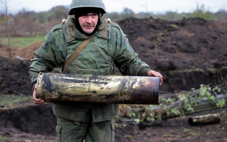 A serviceman carries an artillery shell from a 152-mm howitzer at a position after firing at Ukrainian troops at an undisclosed location in Donetsk - Alexei Alexandrov/AP