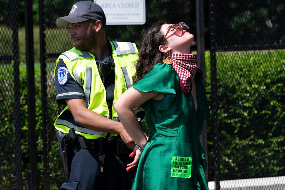 An abortion-rights activist is detained after throwing red paint on the sidewalk outside the Supreme Court in Washington, Saturday, June 25, 2022. The Supreme Court has ended constitutional protections for abortion that had been in place for nearly 50 years, a decision by its conservative majority to overturn the court's landmark abortion cases.