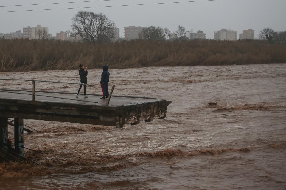 Two people take snapshots atop of a collapsed bridge in Malgrat, near Barcelona, Spain, Wednesday, Jan. 22, 2020. Since Sunday the storm has hit mostly eastern areas of Spain with hail, heavy snow and high winds, while huge waves smashed into towns on the Mediterranean coast and nearby islands of Mallorca and Menorca. (AP Photo/Joan Mateu)