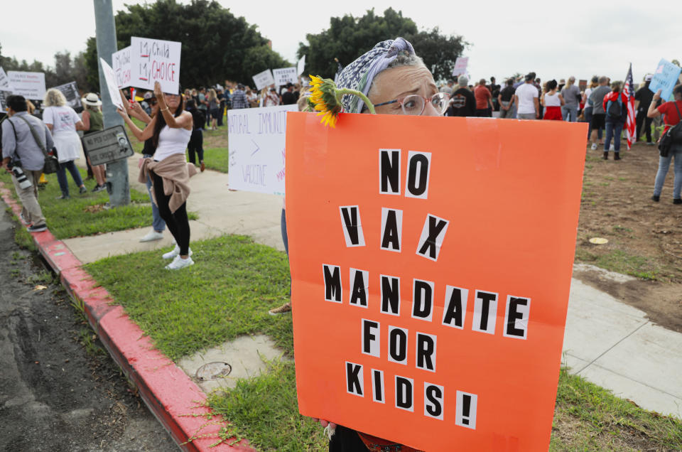 Anti-vaccine protesters hold up signs opposing a vaccine mandate for kids outside the San Diego Unified School District office in San Diego, California.