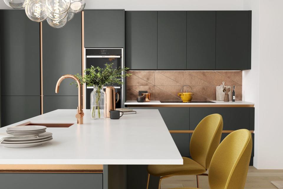 a dark grey kitchen with yellow bar stools and copper accessories