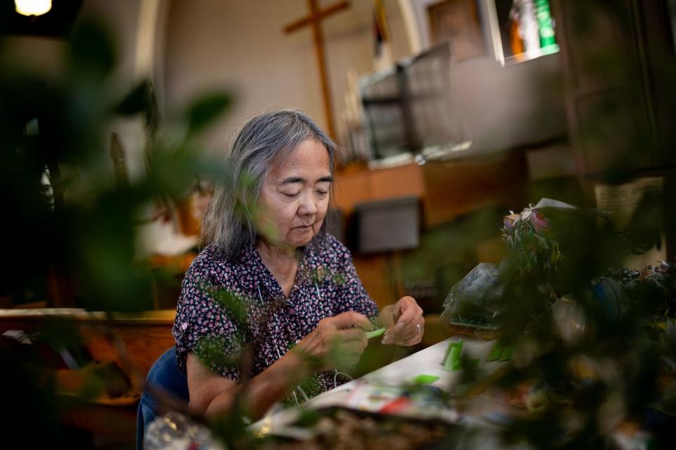 Judy Iwamoto folds origami while surrounded by bonsai trees made by Ken Yamane at Natsu Matsuri, a Japanese culture festival at the Japanese Church of Christ in Salt Lake City on Saturday.