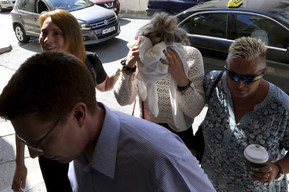 A 19-year old British woman, center, covers her face, as she arrives at the Famagusta court for the first day of her trial, in Paralimni, Cyprus, Wednesday, Oct. 2, 2019. The 19 year old British woman pleaded not guilty to making up an accusation that she was raped by a dozen Israelis at a hotel in a Cypriot resort town. (AP Photo/Petros Karadjias)