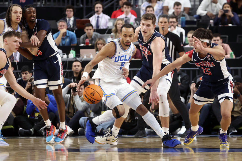 UCLA guard Amari Bailey (5) drives the ball under pressure from Arizona forward Azuolas Tubelis, second from right, and Arizona guard Kerr Kriisa (25) during the first half of an NCAA college basketball game in the championship of the Pac-12 tournament, Saturday, March 11, 2023, in Las Vegas. (AP Photo/Chase Stevens)