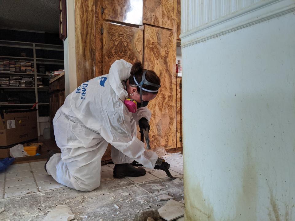 A photo of Laura Spaulding in a white suit working on a house cleanup.