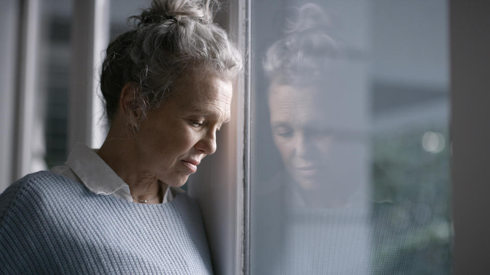 Depression, anxiety and thinking senior woman with a mental health problem in the window reflection of a house. Sad, stress and elderly person with an idea, tired and depressed during retirement