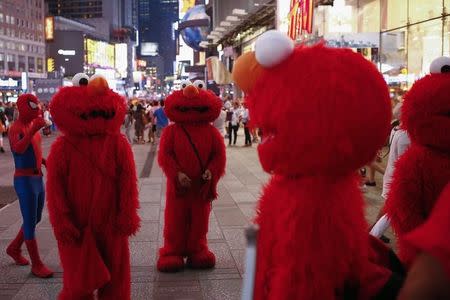 Jorge, an immigrant from Mexico (C), stands amidst other people, all dressed as the Sesame Street character Elmo, while they look to make tips for photographs in Times Square in New York July 30, 2014. NEW YORK REUTERS/Eduardo Munoz