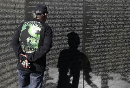 A U.S. military combat veteran stares at a name on the wall of the National Vietnam Veterans Memorial on Veteran's Day in Washington, November 11, 2014. REUTERS/Larry Downing