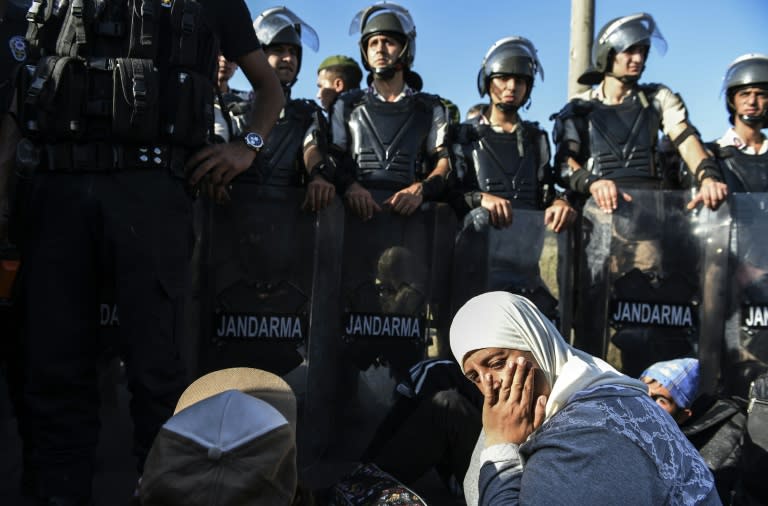 Syian refugees sit in front of a police barricade as they march along the highway towards the Turkish-Greek border at Edirne on September 18, 2015