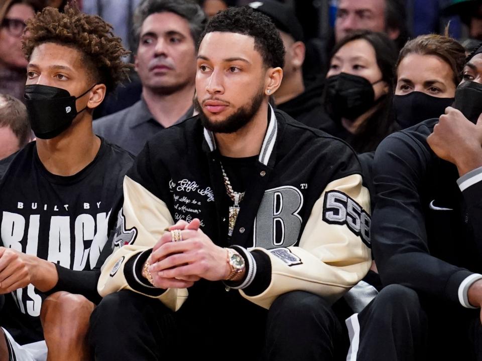 Ben Simmons sits on the Nets bench during a game.