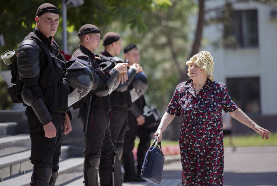 An elderly woman walks by a line of riot policemen standing outside the government headquarters in Chisinau, Moldova, Wednesday, June 12, 2019. Moldova's police chief on Wednesday dismissed six officers who publicly backed a rival government, reflecting a continuing power struggle that has heightened political tensions in the impoverished ex-Soviet nation.(AP Photo/Roveliu Buga)