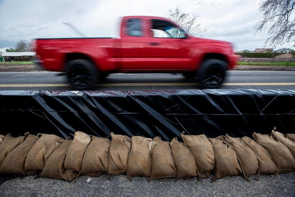 Sandbags and a retaining wall line a section of West North Bear Creek Drive in Merced, Calif., on Tuesday, March 14, 2023.