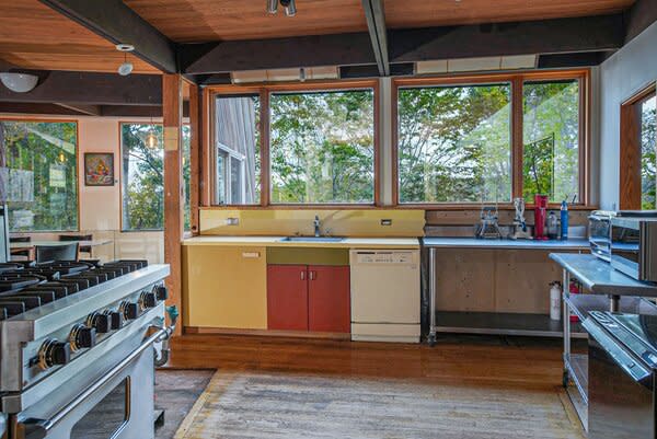 Despite some needed repairs, the kitchen offers an open layout, stainless-steel appliances, and large picture windows overlooking the wooded landscape.