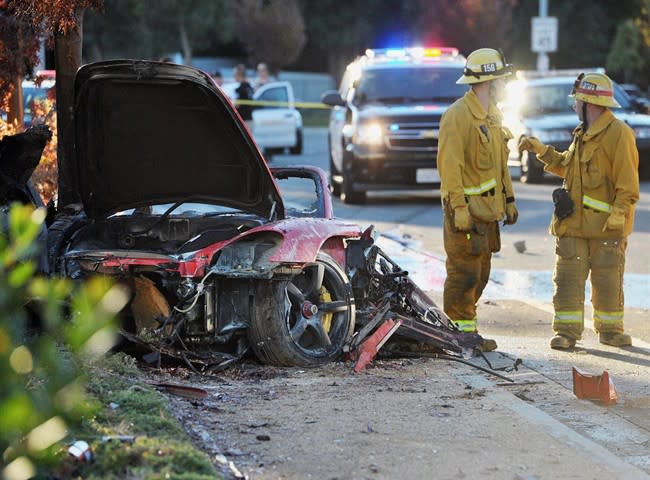 First responders gather evidence near the wreckage of a Porsche sports car that crashed into a light pole on Hercules Street near Kelly Johnson Parkway in Valencia on Saturday, Nov. 30, 2013. A publicist for actor Paul Walker says the star of the