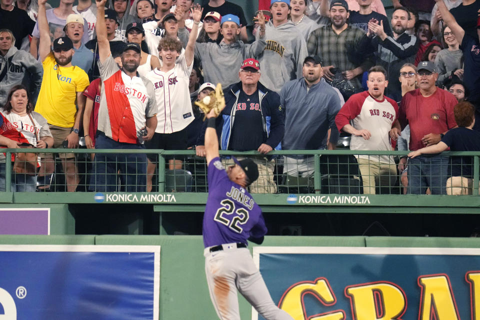 Fans react as Colorado Rockies right fielder Nolan Jones (22) makes the catch on a deep drive by Boston Red Sox's Rafael Devers during the eighth inning of a baseball game at Fenway Park, Monday, June 12, 2023, in Boston. (AP Photo/Charles Krupa)