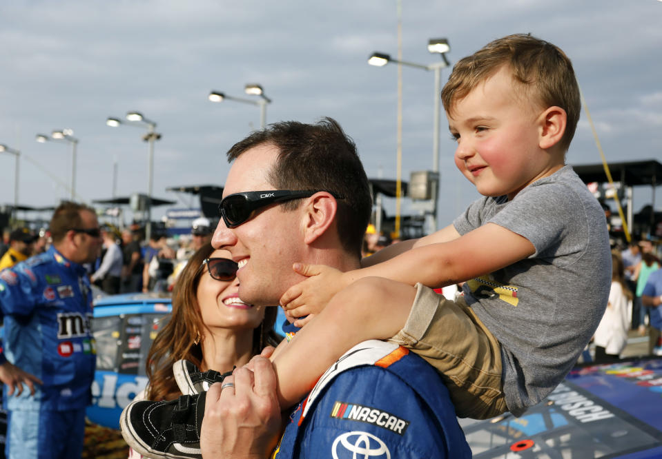 FILE - Kyle Busch carries his 2-year-old son, Brexton, as his wife, Samantha, left, watches before the NASCAR Cup Series auto race at Kansas Speedway in Kansas City, Kan., Saturday, May 12, 2018. Kyle Busch will move to Richard Childress Racing next season, ending a 15-year career with Joe Gibbs Racing because the team could not come to terms with NASCAR’s only active multiple Cup champion. Busch will drive the No. 8 Chevrolet for Childress in an announcement made Tuesday, Sept. 13, 2022, at the NASCAR Hall of Fame. (AP Photo/Colin E. Braley, File)