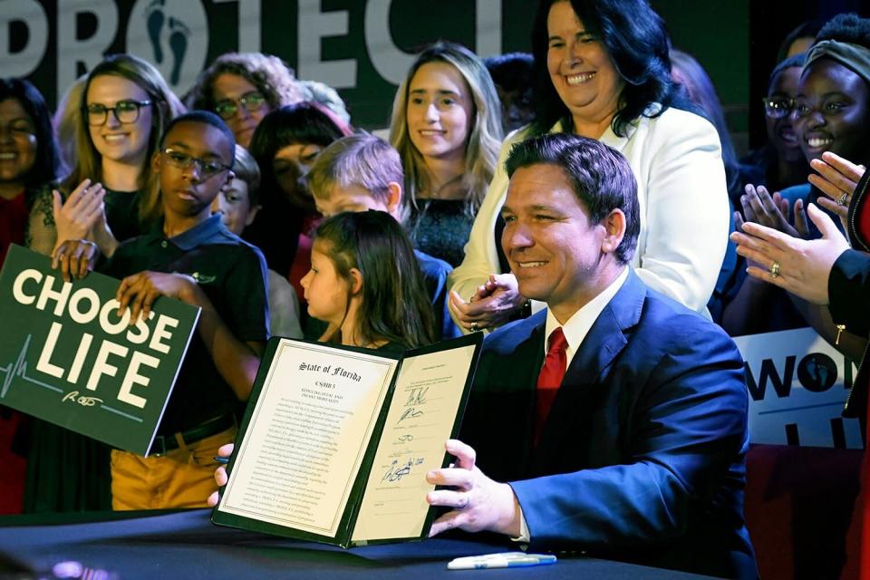 Florida Gov. Ron DeSantis holds up a 15-week abortion ban law after signing it on April 14, 2022, in Kissimmee, Fla. A synagogue claims in a lawsuit filed, that a new Florida law prohibiting abortion after 15 weeks violates religious freedom rights of Jews in addition to the state constitution's privacy protections