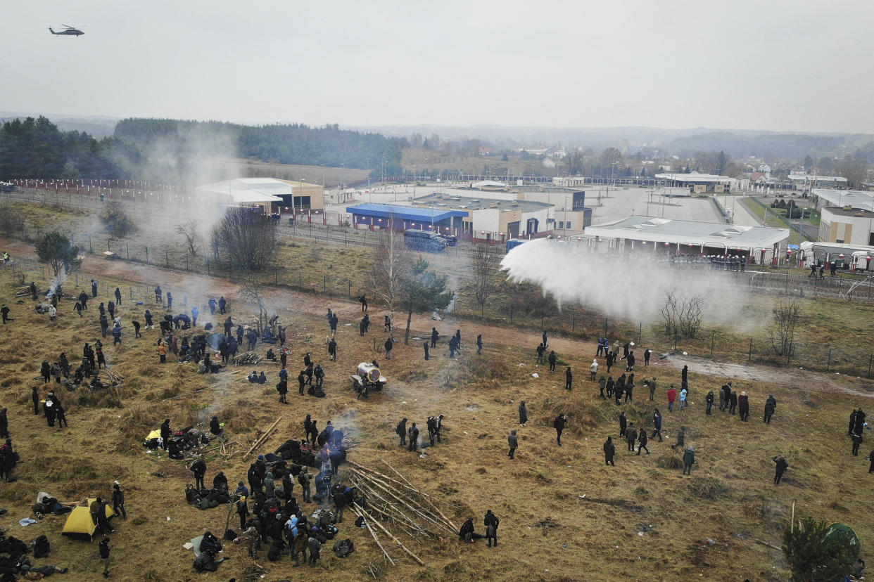 In this image taken with a drone Polish servicemen use a water cannon during clashes between migrants and Polish border guards at the Belarus-Poland border near Grodno, Belarus, on Tuesday, Nov. 16, 2021. Polish border forces say they were attacked with stones by migrants at the border with Belarus and responded with a water cannon. The Border Guard agency posted video on Twitter showing the water cannon being directed across the border at a group of migrants in a makeshift camp. (Leonid Shcheglov/BelTA via AP)