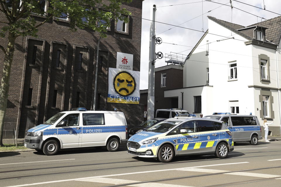 Police vehicles are parked in front of the Don Bosco High School in Essen, Germany, Thursday, May 12, 2022. Police in the western German city of Essen seized weapons from the apartment of a 16-year-old student allegedly plotting an attack on a local school. Local police said Thursday that officers searched the suspect’s apartment overnight and found spears and other sharp weapons. (David Young/dpa via AP)