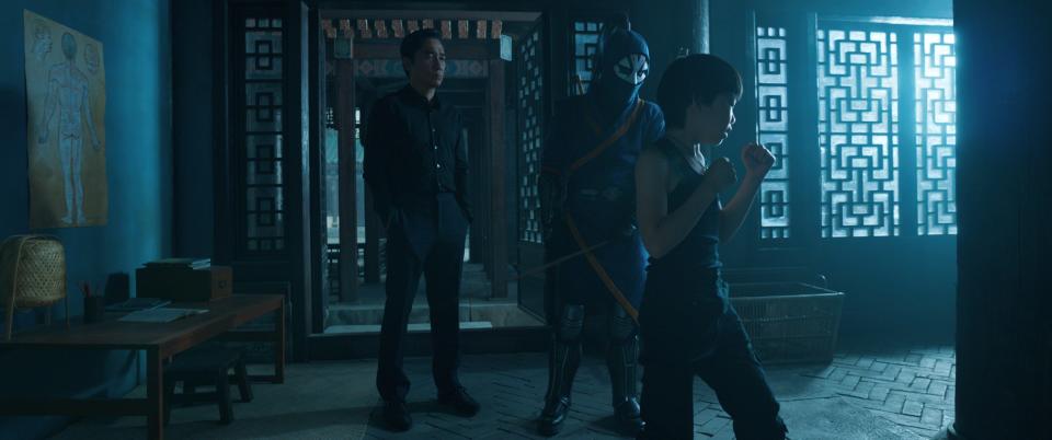 Wenwu (Tony Leung, far left) watches as Death Dealer trains his son Shang-Chi (Jayden Tianyi Zhang) in in "Shang-Chi and the Legend of the Ten Rings."