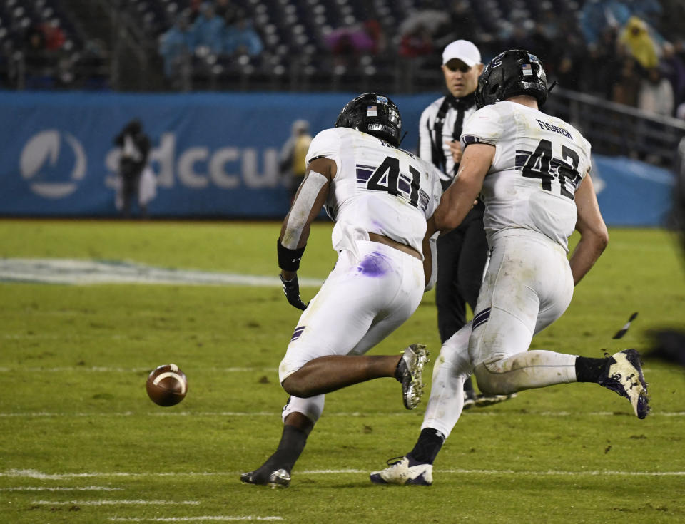 Northwestern safety Jared McGee (41) picks up a fumble next to linebacker Paddy Fisher (42) during the second half of the Holiday Bowl NCAA college football game against Utah Monday, Dec. 31, 2018, in San Diego. McGee returned the fumble for an 86-yard touchdown. (AP Photo/Denis Poroy)