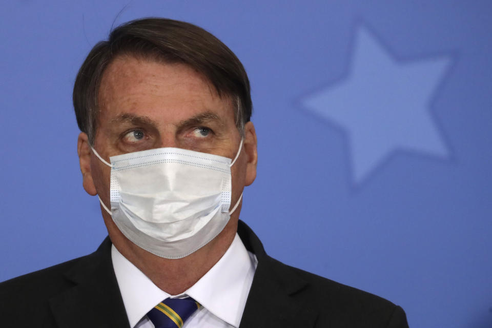 Brazil's President Jair Bolsonaro wearing a protective mask to curb the spread of the new coronavirus, attends the launching ceremony of a rights guarantee program for rural women, at the Planalto Presidential Palace in Brasilia, Brazil, Wednesday, July 29, 2020. (AP Photo/Eraldo Peres)