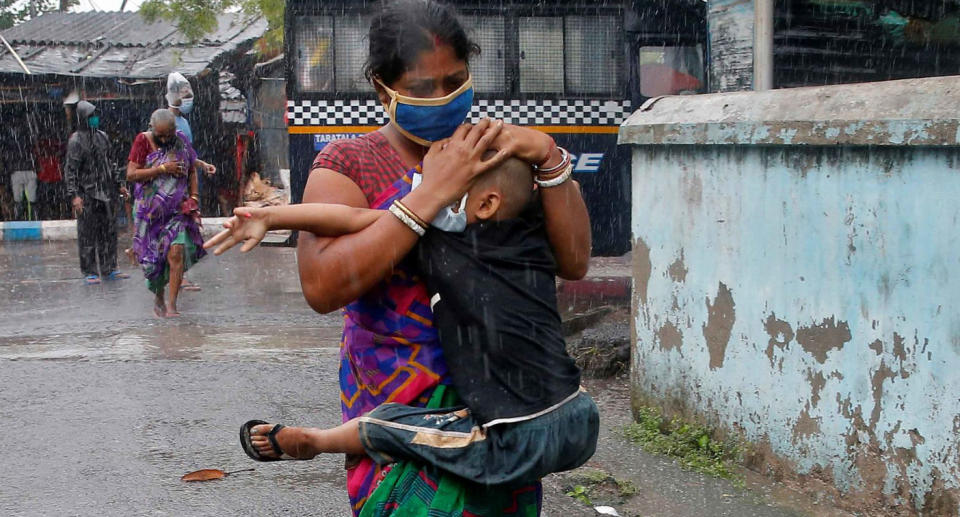 A woman shown clutching her child in heavy rain as they evacuate a slum in Kolkata. Source: Reuters