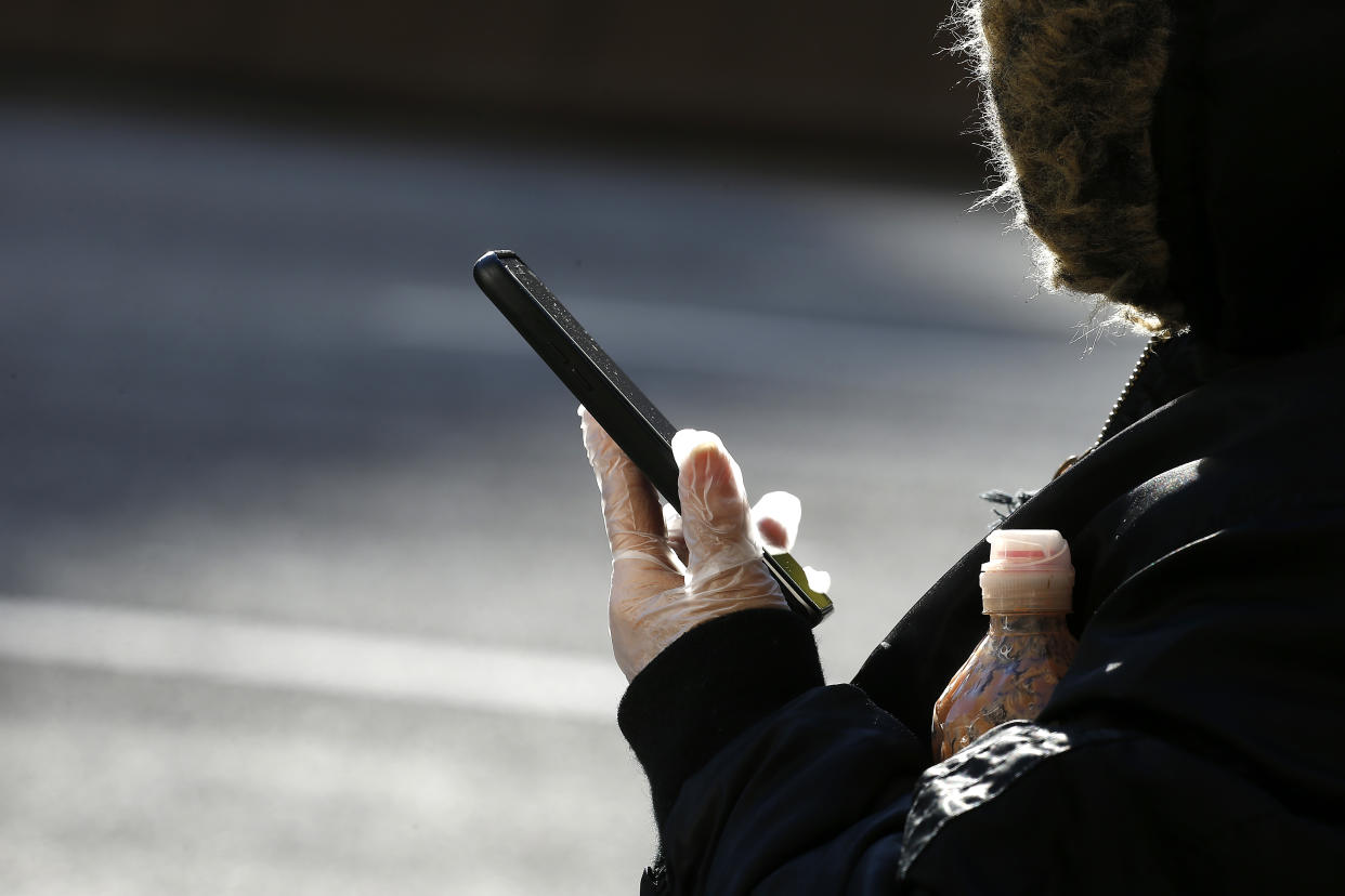 A woman wears a plastic glove while holding her cell phone on April 9, 2020 in New York City. (Photo by John Lamparski/Getty Images)