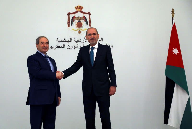 Jordan's Foreign Minister Ayman Safadi shakes hands with Syria's Foreign Minister Faisal Mekdad in Amman