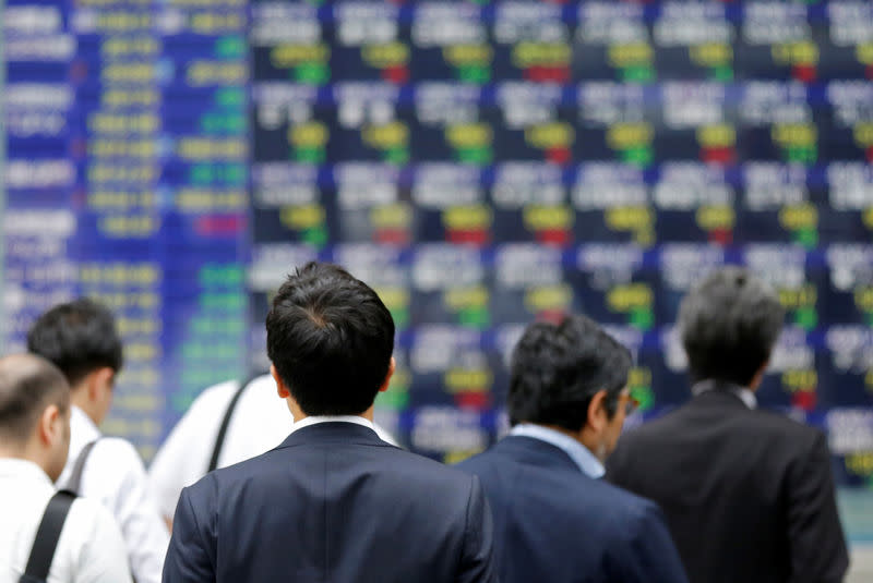 People walk past an electronic stock quotation board outside a brokerage in Tokyo, Japan, September 22, 2017. REUTERS/Toru Hanai