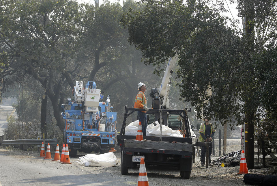 In this Wednesday, Oct. 18, 2017 file photo, PG & E electrical crews work on restoring power to a residence damaged by wildfires in Glen Ellen, Calif. Facing potentially colossal liabilities over deadly California wildfires, PG&E will file for bankruptcy protection. The announcement Monday, Jan. 14, 2019, follows the resignation of the power company's chief executive. (AP Photo/Ben Margot)