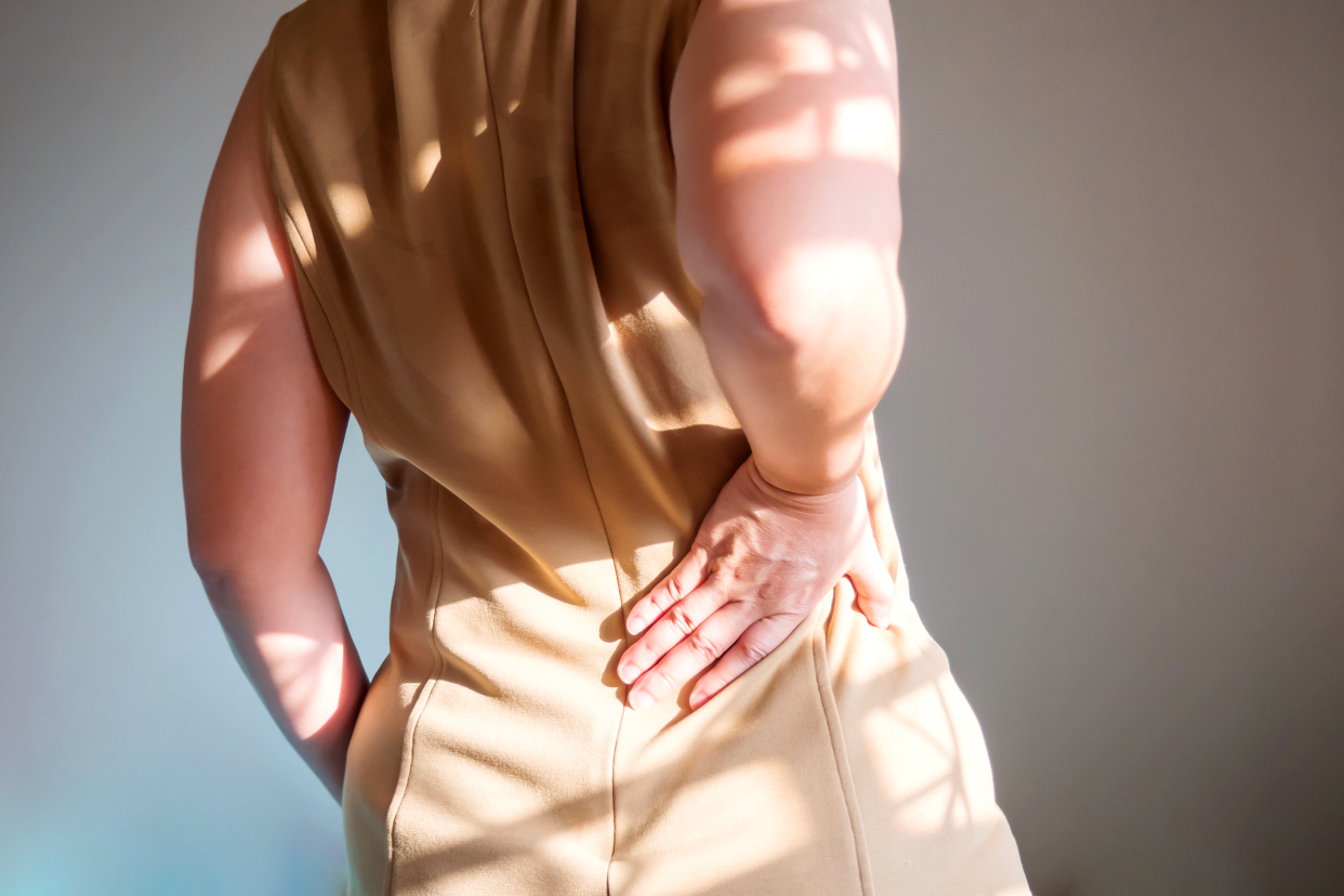 Woman holding her lower back experiencing kidney pain