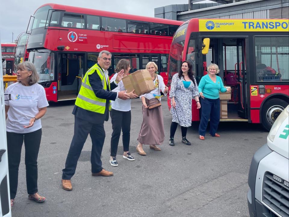 Mike Bowden, chair of SHAP, (2L) works with others Swindon aid workers to load up the London red bus with supplies for Ukraine (Provided)