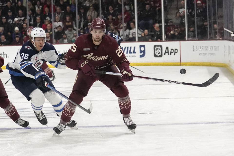 Winnipeg Jets' Morgan Barron (36) and Arizona Coyotes' Justin Kirkland (25) chase down the puck during the first period of an NHL hockey game Sunday, Jan. 7, 2024, in Tempe, Ariz. (AP Photo/Darryl Webb)