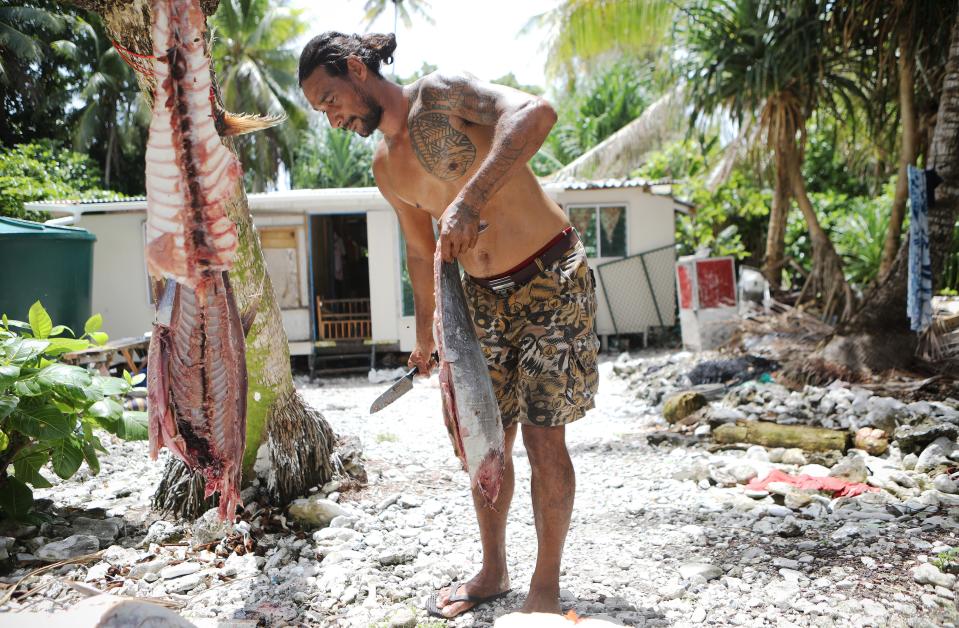 A fisherman cuts up a tuna in front of his home on November 23, 2019 in Funafuti, Tuvalu.