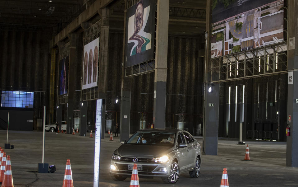 People take in an art exhibit from their car as they drive through a warehouse displaying paintings and photos in Sao Paulo, Brazil, Friday, July 24, 2020, amid the new coronavirus pandemic. Galleries, cinemas, theaters and museums are closed due to the restrictive measures to avoid the spread of COVID-19, but a group of artists and a curator found a way to overcome the restrictions to share their art with the residents of Brazil’s largest city. (AP Photo/Andre Penner)