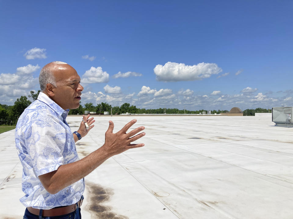 In this photo taken on June 6, 2022, Neil Bernard, pastor of New Wine Christian Fellowship in LaPlace, La., gestures to where solar panels will be installed on the roof of part of his church. New Wine is part of the Community Lighthouse program designed to outfit select locations in southeast Louisiana with solar panels and batteries so they can maintain power in extended outages and serve as hubs to take care of people in their communities. (AP Photo/Rebecca Santana)